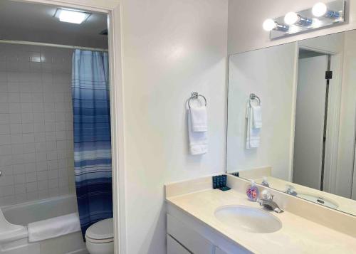 a bathroom with a sink and a toilet and a mirror at 1414- Heart of Waikiki with Kitchen - Free Parking - City View in Honolulu