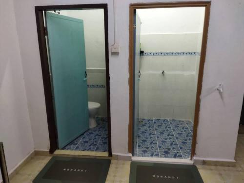 a bathroom with a shower and a toilet and a mirror at Ustazah Homestay in Kampong Ru Sepuloh