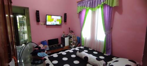 een slaapkamer met een bed en een tv aan de muur bij Alesya Homestay 