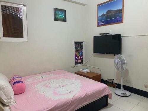 Schlafzimmer mit einem rosa Bett und einem Flachbild-TV in der Unterkunft Hai Zhi Dao Min Su in Magong