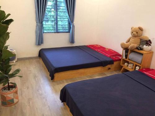 Un dormitorio con 2 camas y un osito de peluche sobre una mesa. en Tam An Lakeview House, en Buon Ma Thuot