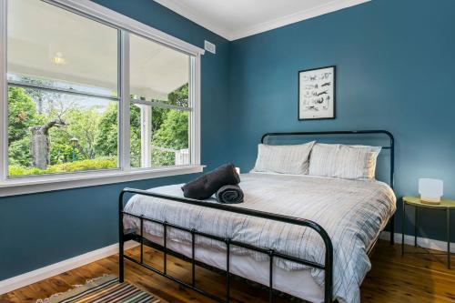 a blue bedroom with a bed and a window at Garden Cottage in Leura