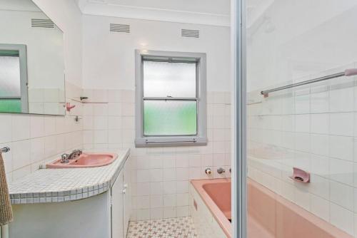 a bathroom with a pink sink and a shower at Garden Cottage in Leura