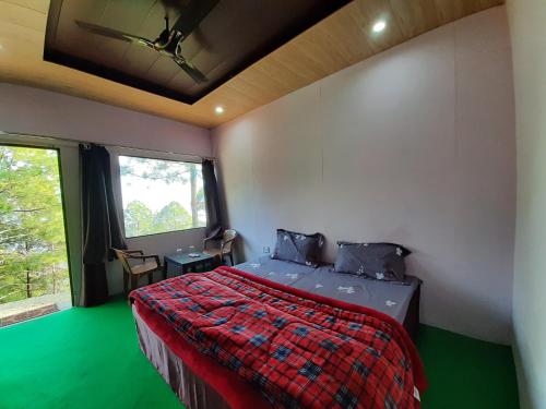 ランズドーンにあるRohini Village Homestayのベッドルーム1室(赤と緑の掛け布団付きのベッド1台付)