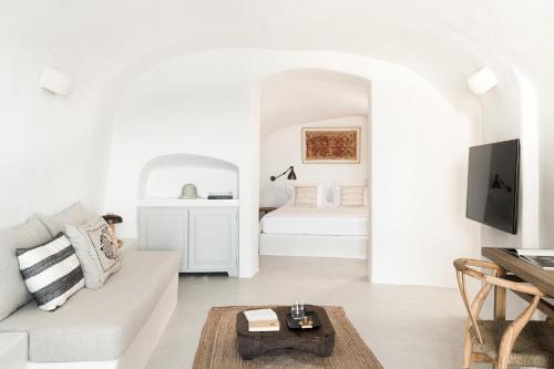 a white living room with a white couch and a bed at Armenaki in Oia