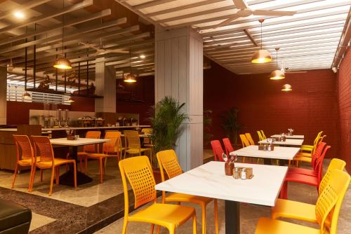 un restaurante con mesas blancas y sillas amarillas en Hotel Anand Heritage, en Shirdi