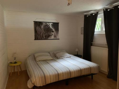 Una cama en un dormitorio con una foto de un león en Le Clapot- Les Iris, en Saint-Étienne