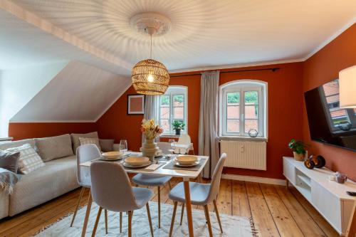 ein Wohnzimmer mit orangefarbenen Wänden sowie einem Tisch und Stühlen in der Unterkunft Moderne Ferienwohnung mit Festungsblick im Zentrum in Königstein an der Elbe