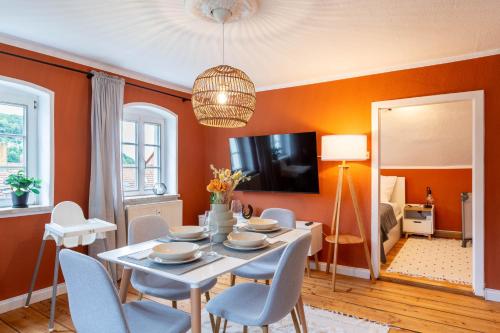 ein Esszimmer mit orangefarbenen Wänden sowie einem Tisch und Stühlen in der Unterkunft Moderne Ferienwohnung mit Festungsblick im Zentrum in Königstein an der Elbe
