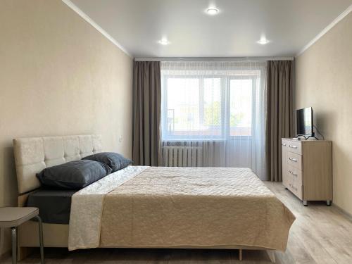 um quarto com uma cama, uma televisão e uma janela em Маг Подарки, Конституции, парк, Рахмет em Petropavl