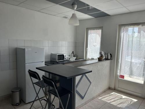 a kitchen with a refrigerator and a table and chairs at Studio bien placé (100 m gare) in La Ferté-Saint-Aubin