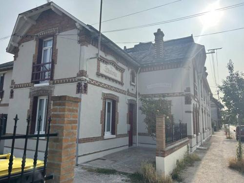 une grande maison blanche avec un portail en face de celle-ci dans l'établissement Studio bien placé (100 m gare), à La Ferté-Saint-Aubin