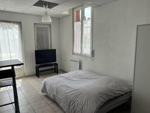 a white bedroom with a bed and a television at Studio bien placé (100 m gare) in La Ferté-Saint-Aubin