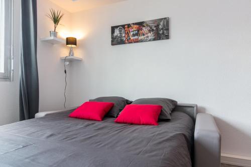 una camera con un letto con due cuscini rossi di SWEETHOME DIJON - ALBERT 1er a Digione