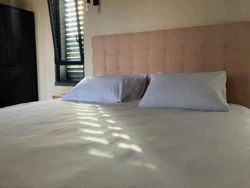 a large white bed with two pillows and a window at בסנדלים: חאן בוטיק בגולן in Ma'ale Gamla