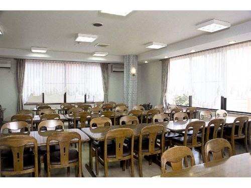 an empty room with tables and chairs and windows at Sunshine Kyohei in Nozawa Onsen