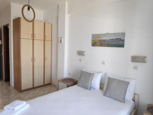 a bedroom with a white bed and a cabinet at Villa Dora Studios in Batsi