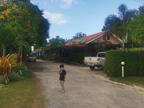 a little boy standing in the middle of a dirt road at Numhom Resort in Ban Nong Chum Saeng