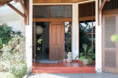 a cat sitting in front of a wooden door at 3BR AC Rumah Liburan Pasteur Bandung in Bandung