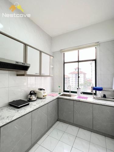 a kitchen with white counters and a large window at Costa Mahkota Suites Malacca Central By Nestcove in Melaka