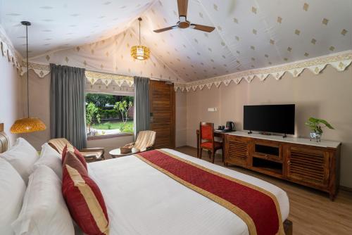 una camera da letto con un letto grande e una TV a schermo piatto di Aranya Vilas - A Nature Resort a Udaipur