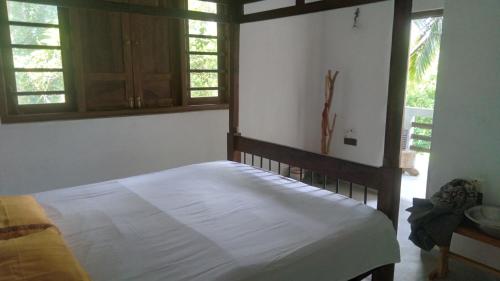 a bedroom with a bed in a room with windows at Osu Lena Habaraduwa in Habaraduwa
