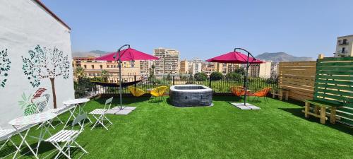 a patio with chairs and tables and a pool with grass at I Sollazzi in Palermo