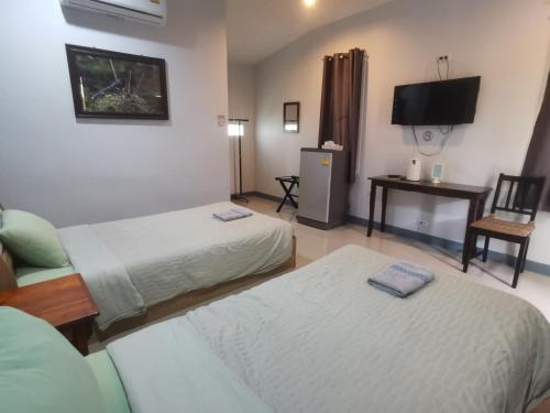 a hotel room with two beds and a tv at Numhom Resort in Ban Nong Chum Saeng