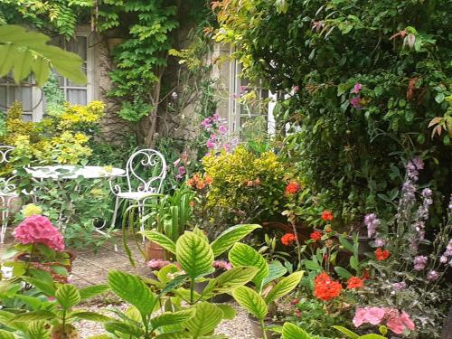 a garden with a table and chairs and flowers at la glycine in Asnelles