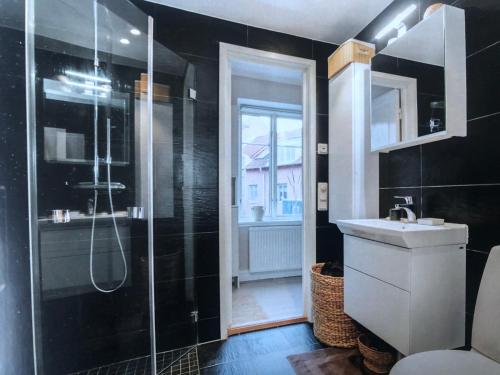 a black bathroom with a shower and a sink at Room, central location in Halmstad