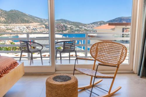 a room with chairs and a balcony with a view at Kalkan Saray Suites Hotel in Kalkan