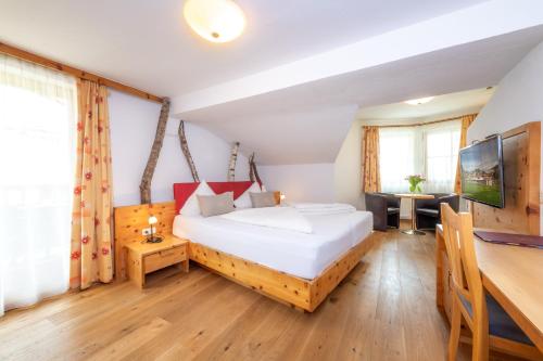 a bedroom with a large bed and a desk at Vitalhotel Sonnenhof in Going