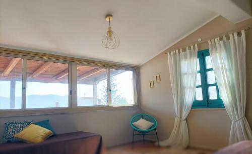 a living room with windows and a couch and a chair at Villemar in Isola delle Femmine