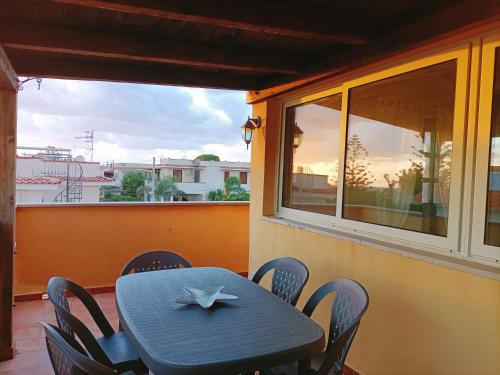 a blue table and chairs on a balcony with a window at Villemar in Isola delle Femmine