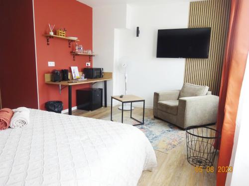 une chambre avec un lit, une chaise et une télévision dans l'établissement Intello - studio tout confort centre-ville Nogent-le-Rotrou, à Nogent-le-Rotrou