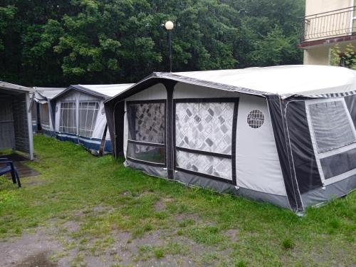 a row of tents parked in a yard at Domki letniskowe Przyczepy kempingowe Zacisze Mielno in Mielno