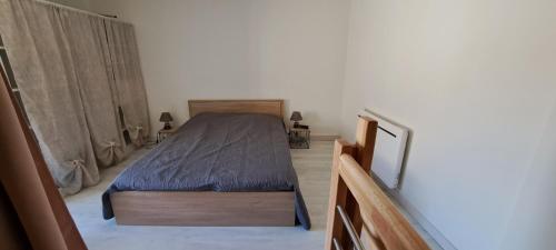 een slaapkamer met een bed met een blauwe sprei bij Maison de bourg in Jumeaux
