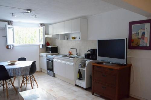 une cuisine avec une télévision au-dessus d'une table dans l'établissement Studio 35m2 climatisé, 10mn des calanques, à La Ciotat