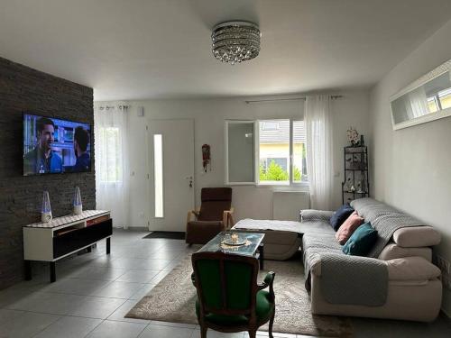 ein Wohnzimmer mit einem Sofa und einem TV in der Unterkunft maison neuve au porte de paris in Bagneux
