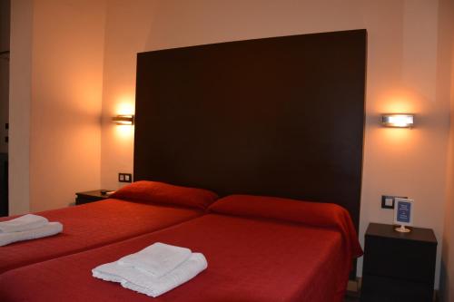a bedroom with a red bed with two towels on it at Center Gran Via in Barcelona