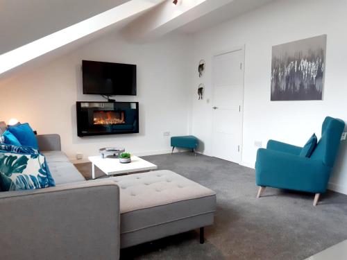 a living room with a couch and chairs and a tv at No's 2 and 5 Llewelyn Apartments in Llanberis