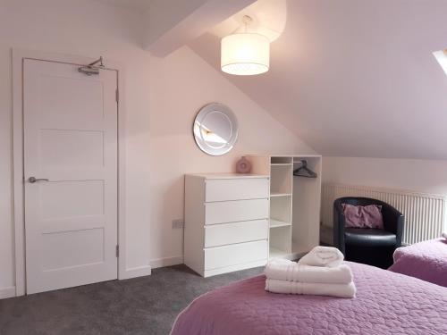 a bedroom with a purple bed and a chair at No's 2 and 5 Llewelyn Apartments in Llanberis