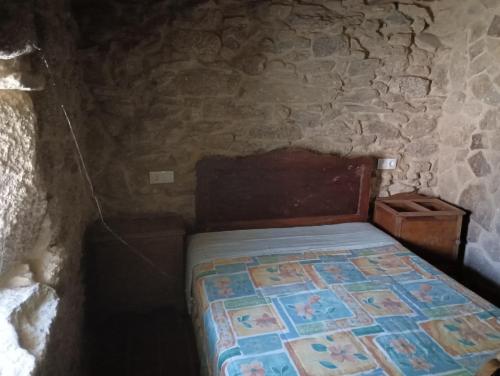 a bedroom with a bed in a stone wall at SANTA LUCIA AREAS in Pontevedra