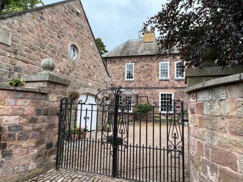 um portão de ferro em frente a um edifício de tijolos em The Coach House Harthill em Harthill