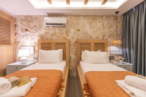 a bedroom with two beds and a stone wall at Kalkan Saray Suites Hotel in Kalkan