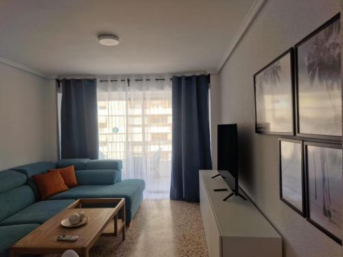 a living room with a blue couch and a tv at Apartamento Mar y Arena in Cullera