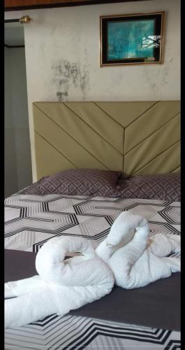 a bed with two white towels on it at Naca Homestay in Manado