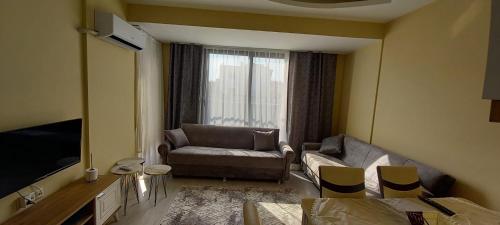 a living room with a couch and a television at kusadası, davutlar mah. 1+1 mobilyalı site içinde yazlık daire in Kusadası