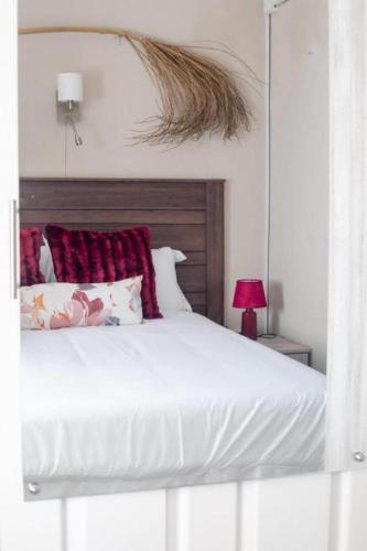 a bedroom with a white bed with red pillows at Birdville BNB Guest House in Gaborone