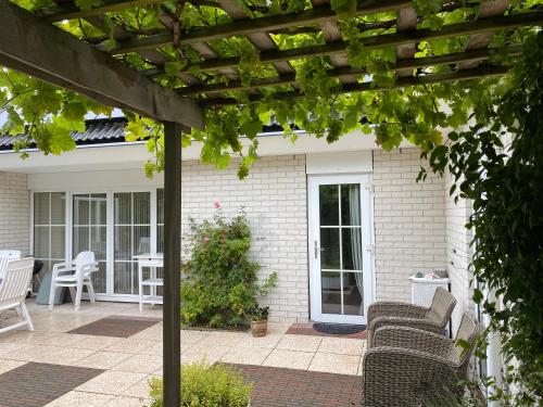 eine Pergola mit Stühlen und einem Tisch auf der Terrasse in der Unterkunft Lonestar Appartement in Burgh Haamstede